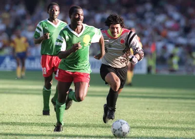 Roger Milla (trái) tung cú nước rút vượt qua thủ thành Rene Higuita của Colombia tại World Cup 1990.