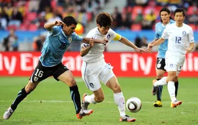 Đội trưởng Hàn Quốc Park Ji-Sung (phải) nỗ lực vượt qua sự truy cản của hậu vệ Maximiliano Pereira (16, Uruguay).