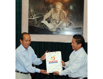 SGGP editor-in-chief Tran The Tuyen (R) gives a present to Director General of Paxaxon Newspaper, Bualaphanh Thanphilom (Photo: SGGP)