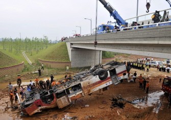 South Korean police and firefighters recover the wreckage of the bus on July 3 2010. AFP