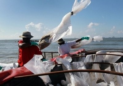 Workers toss bags full of sand contaminated with oil into a dumpster in Louisiana