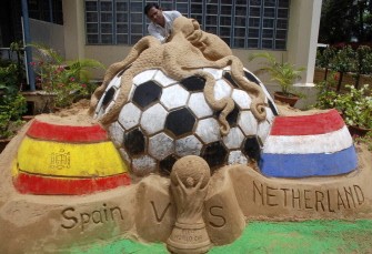 An Indian artist puts the finishing touches to a sand sculpture ahead of the World Cup final between Spain and the Netherlands, depicting a football covered with an octopus in India's Bhubaneswar on July 10, 2010. AFP