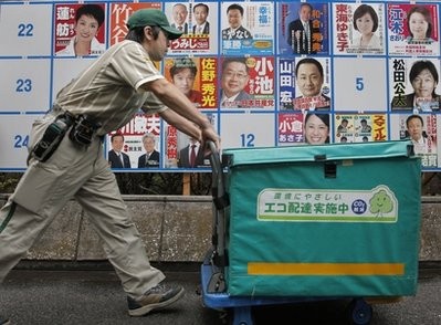 A delivery person pushes a cart in front of posters of candidates for the July 11 upper house elections in Tokyo Friday, July 9, 2010.