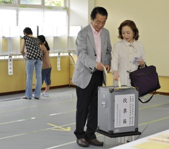Japanese PM Naoto Kan (C) and his wife Nobuko (R) place their ballots into the box at a polling station in Tokyo on July 11, 2010. AFP