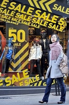 A South Korean woman walk pasts commercial signs in a shopping district of Seoul in January 2010.