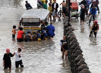 People push a stalled passenger jeepney along a street in Paranaque suburban Manila on July 14, 2010 after Typhoon Conson hit the country's capital late on July 13. AFP photo
