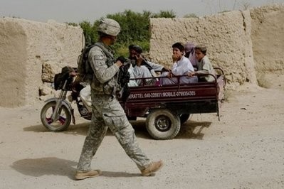 A US soldier from 1st Platoon Bravo Troop of 1st Squadron, 71st Cavalry walks past Afghans on a three-wheeler vehicle during a patrol in the Dand district of Kandahar Province in Afghanistan.