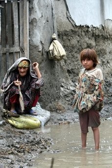 A woman sits outside her house flooded by heavy monsoon rains in Peshawar, Pakistan on Friday, July 30, 2010.