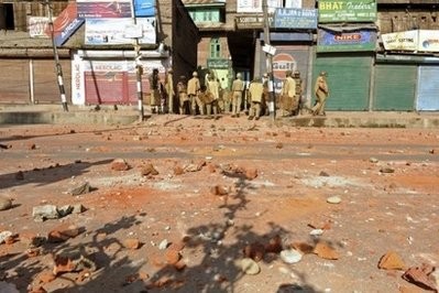 Indian police gather near shops during clashes with demonstrators in Srinagar on July 30