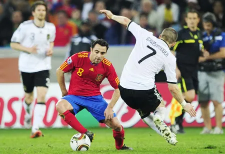 Tiền vệ Xavi (trái, Tây Ban Nha) đi bóng qua tiền vệ tuyển Đức Bastian Schweinsteiger