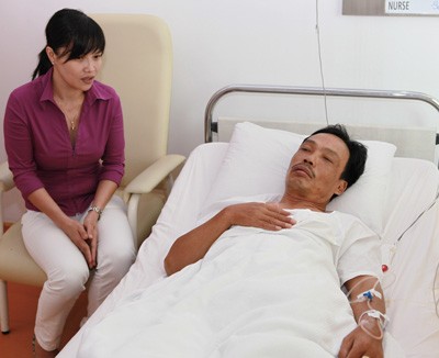 Phung Anh Tu (L), representative of of Minh Duc restaurant, visits Le Van Ngai in the hospital on July 31 (Photo: SGGP)