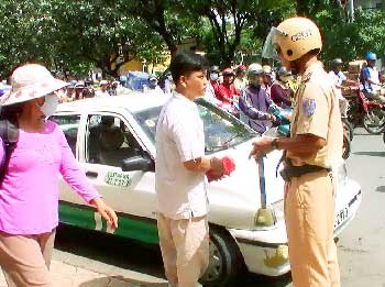 A transport police official slaps a cabdriver with a fine for operating a falsified cab in HCMC (Photo: SGGP)