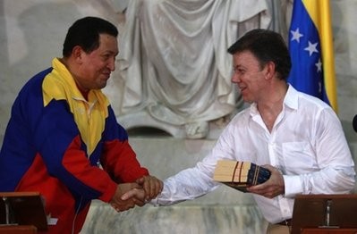 Colombia's President Juan Manuel Santos, right, receives, from Venezuela's President Hugo Chavez, a biography of Simon Bolivar by Felipe Larrazabal as a present during a joint press conference in Santa Marta, Colombia, Tuesday, Aug. 10, 2010