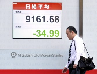 A man walks in front of a share price board in Tokyo on August 17, 2010