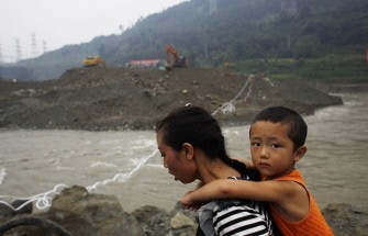 A villager carries her son as she walks in front of rescuers preparing to use explosives to clear a blockage in the Mingjiang river, caused by the debris from the landslide caused by torrential rains in Yingxiu town -- the epicentre of the Sichuan earthquake-- in southwest China's Sichuan province on August 17, 2010. AFP