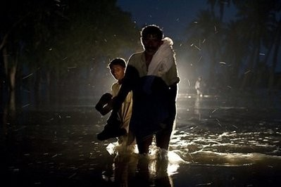 A Pakistani man walks with a boy as they wade through flood water near Basira village in Punjab.