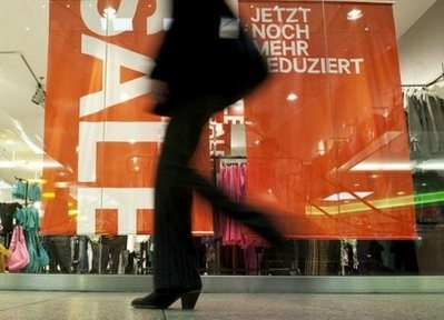 A woman walks past a shop window displaying a Sale sign at a shopping mall in Berlin.