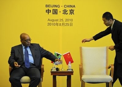 South Africa President Jacob Zuma, left, pours water into a glass as a Chinese waitstaff tries to help him during a news conference in Beijing, China Wednesday, Aug. 25, 2010.