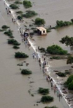 Pakistanis walk across a flooded area in the southern city of Thatta on August 29, 2010