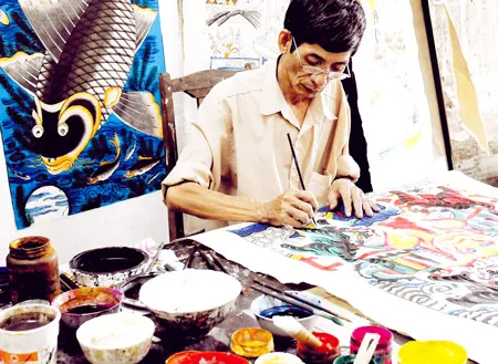 Nghệ nhân Lê Đình Nghiên làm việc cần mẫn bên những bức tranh.