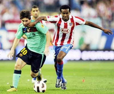 Lionel Messi (trái) vượt qua Paulo Assuncao của Atletico Madrid. Ảnh: AFP