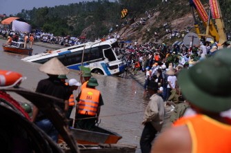Thousands of people watch the bus being pulled up from the Lam River on October 21, 2010. AFP