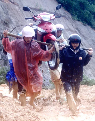 Phải 4 - 5 người mới khiêng hoặc dắt được xe máy qua đoạn sạt lở trên đèo Hòn Giao thuộc địa phận huyện Khánh Vĩnh (Khánh Hòa) . Ảnh: NAM VIÊN