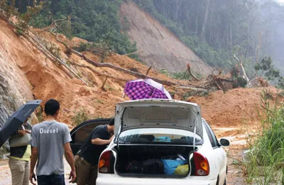Hành khách bị mắc kẹt, phải khuân vác hành lý “tăng bo” qua đoạn sạt lở. Ảnh: Nam Viên