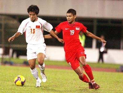 Vietnamese striker Quang Hai (left, in white) vies against a Singapore defender in an AFF Cup 2008 game (Photo: Dung Phuong)