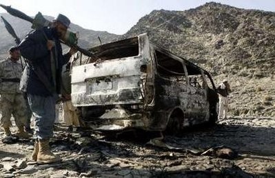 An Afghan border policeman keeps watch next to burnt vehicles belonging to a team of Afghan deminers who were kiddnapped by the Taliban in Momand Dara, December 1, 2010.