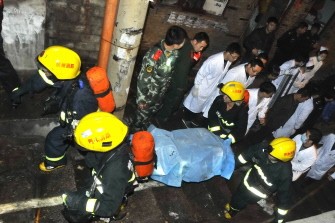 Chinese firefighters remove a body of a victim from the rubble of the Internet cafe on Dec. 4. AFP