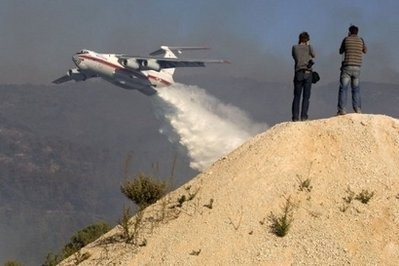 Photographers take pictures as an Ilyushin-76 tanker plane sprays flames in the Carmel Forest on the outskirts of Haifa. AFP