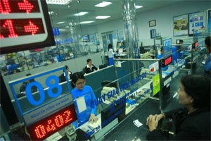 A cash teller (left, in blue) talks with a client at the Asia Commercial Bank (Photo: Minh Tri)