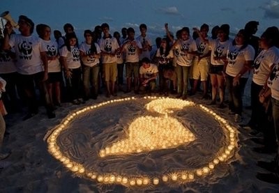 (AFP) Members of WWF make a representation of the Earth with lit candles on a beach in Cancun.