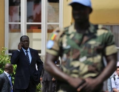 Ivory Coast's former premier and presidential election candidate Alassane Ouattara (L) talks on phone nearby a UN soldier in Abidjan