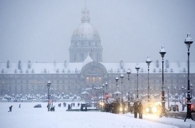 People walk on a snow covered street in front of the Invalides museum in Paris