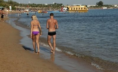 A tourist couple walks in the shallow waters at a closed beach in the Red Sea resort of Sharm el-Sheik, Egypt Wednesday, Dec. 8, 2010.