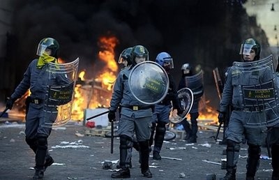Policemen walk at Piazza del Popolo after clashes with youths during a protest to demand a change of government