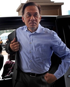 AFP file - Anwar Ibrahim puts on his jacket as he arrives at the court in Kuala Lumpur on August 16, 2010 to attend his ongoing sodomy trial.