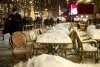 People walk past snow covered chairs and tables at a restaurant in Berlin.