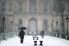 Pedestrians walk on a snow-covered Pont des Arts towards the Louvre Museum in Paris, as heavy snow disrupts the Christmas holiday getaway in Europe, forcing the continent's biggest airports to close