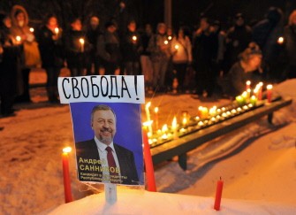 Belarus opposition supporters light candles near a picture of jailed opposition presidential candidate Andrey Sannikov at a prison's wall in Minsk during a demonstration on December 21, 2010. AFP