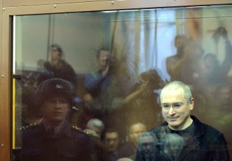 Mikhail Khodorkovsky (R) stands behind a glass wall at a courtroom in Moscow, on December 27, 2010. AFP