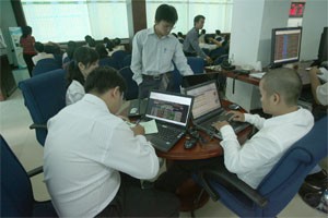 Two brokers (in front) watch listed companies' profile on their laptop at a HCMC-based brokerage (Photo:Minh Tri)