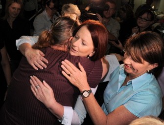 Australian Prime Minister Julia Gillard (C) hugs displaced resident Sandy Kiddle (L) as Queensland Premier Anna Bligh (R) looks on during a visit to an evacuation centre in Bundaberg on December 31, 2010. AFP