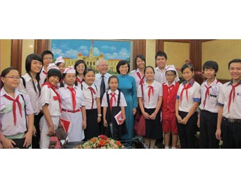 Chairman of Ho Chi Minh City People's Committee Le Hoang Quan (black cravat) and the Chairwoman of city People's Council Pham Phuong Thao (C) pose a photo with students taking part in the meeting on January 1, 2011. (Photo:SGGP