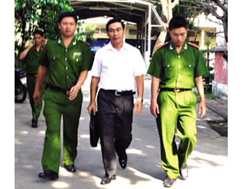 Nguyen Huu Long (C) is taken in custody in HCM City on January 10 (Photo: Thanh Nien)