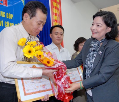 Ms Nguyen Thi Nhu Thuy (R), vice chairperson of city’s counsel for prize and discipline hands certificates to businessmen
