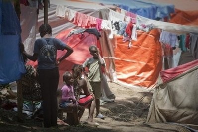 A family gathers outside their temporary tent home in the impoverished neighbourhood of Petionville, Haiti.