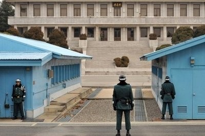 Soldiers from South Korea (R) and North Korea (C-far) stand guard on their respective sides at the truce village of Panmunjom in the Demilitarized Zone (DMZ) separating the two Koreas in December 2010